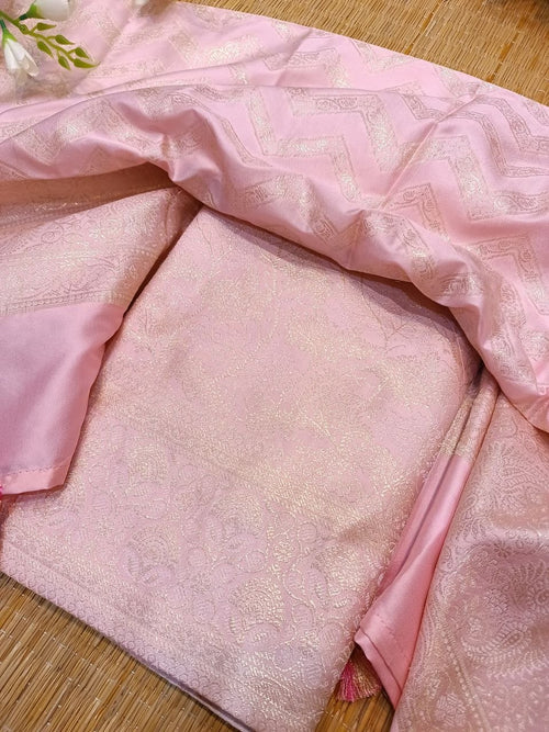Pink fabric with gold patterns on a wooden surface